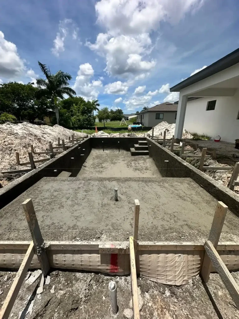 Concrete pool construction progress with wooden formwork.