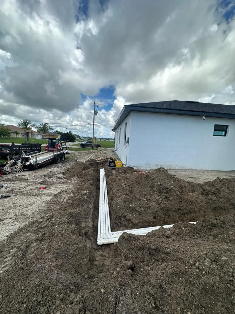 Trenches with pool piping laid alongside a house.