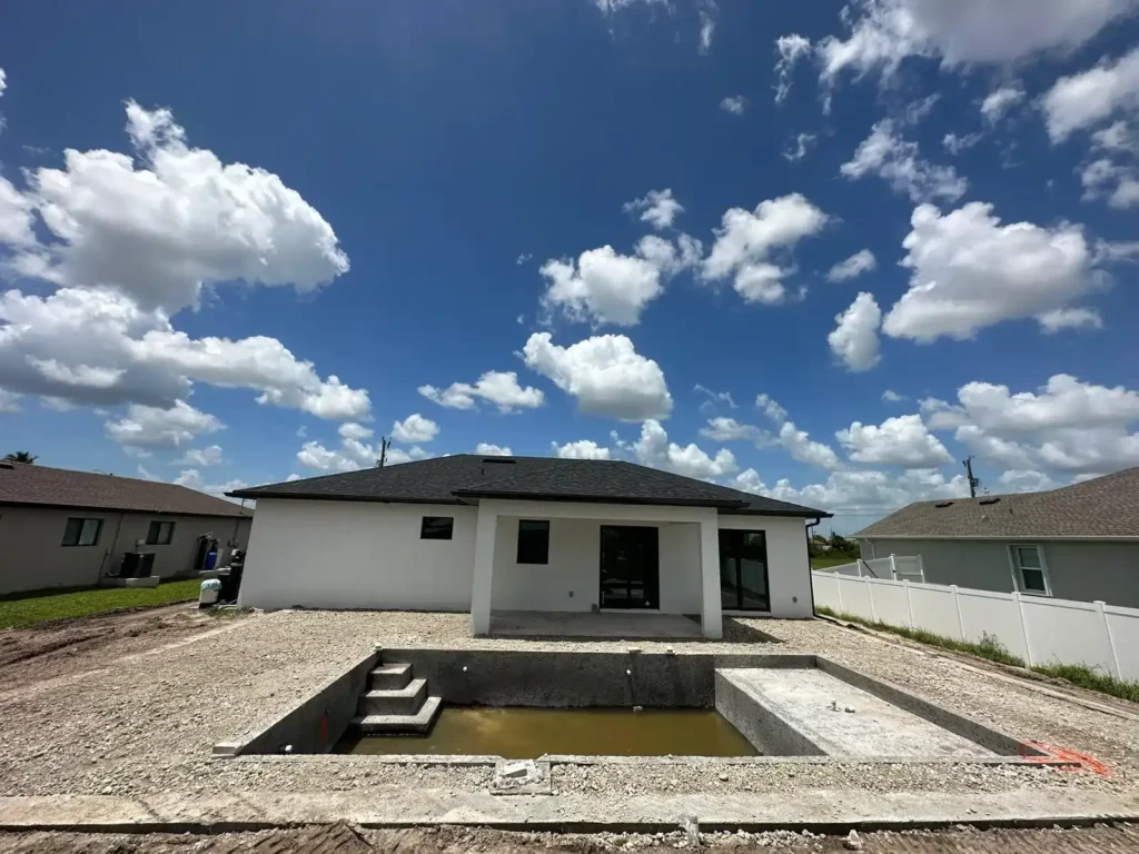 A backyard pool under construction, ready for finish work, with clear skies in the background.