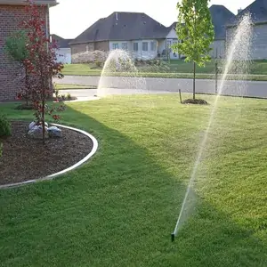 Lawn being watered by an irrigation system in a suburban neighborhood.