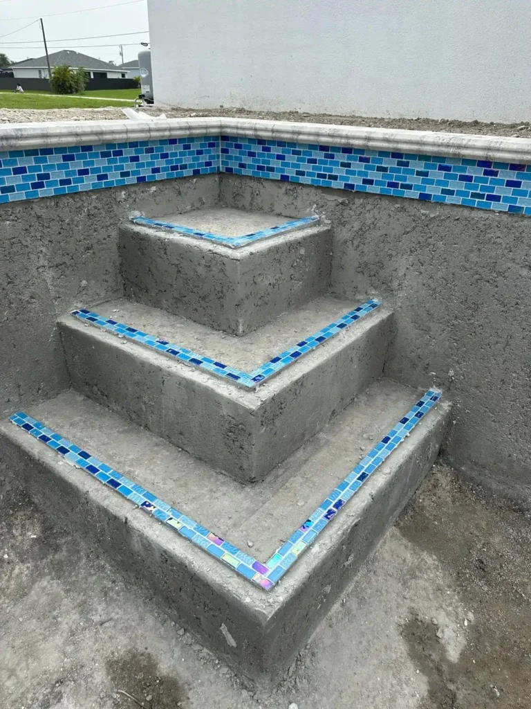 Tile strips being installed on pool steps.