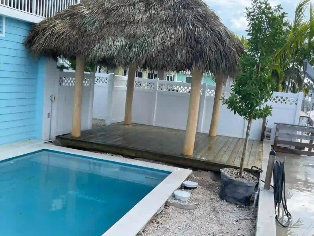 Simple tiki hut on a wooden platform next to a pool.