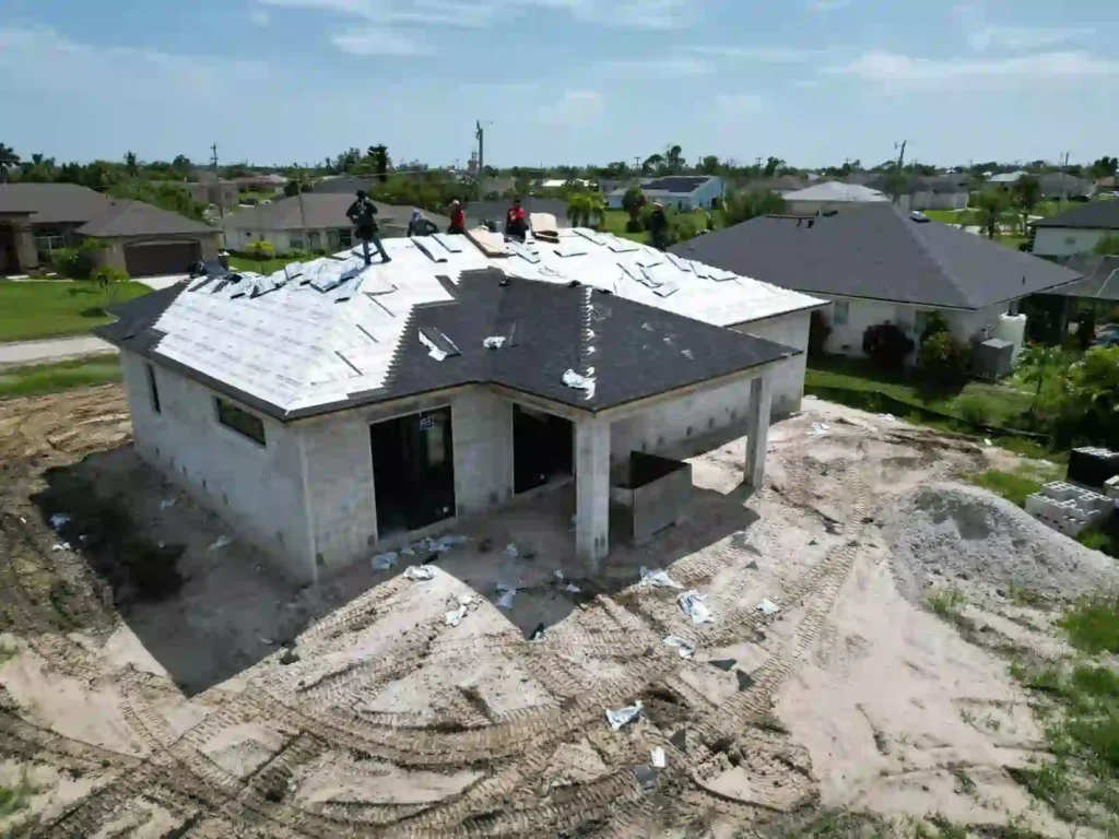 Crew installing shingles on a house roof.