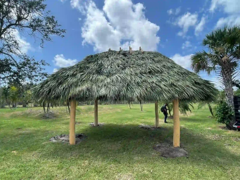 Tiki hut on a field providing shade for outdoor activities.