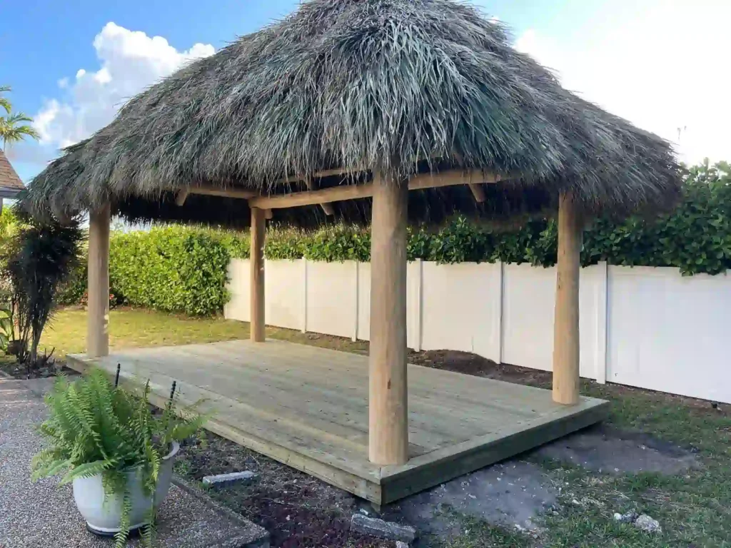 Tiki hut with freshly installed thatch on a green field.